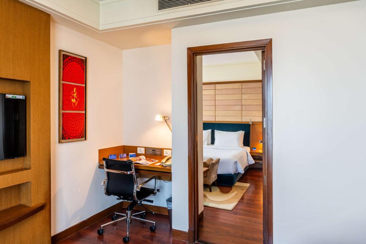 a hotel room with a bed and a desk and a bedroom at Radisson Blu Hotel, Indore in Indore