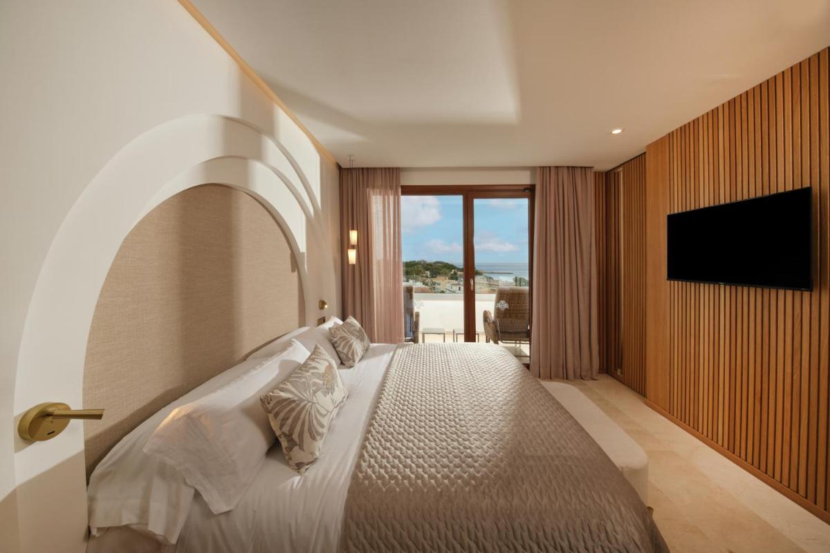 Un dormitorio con una cama con un televisor en la pared. en Hotel Son Caliu Spa Oasis, en Palmanova