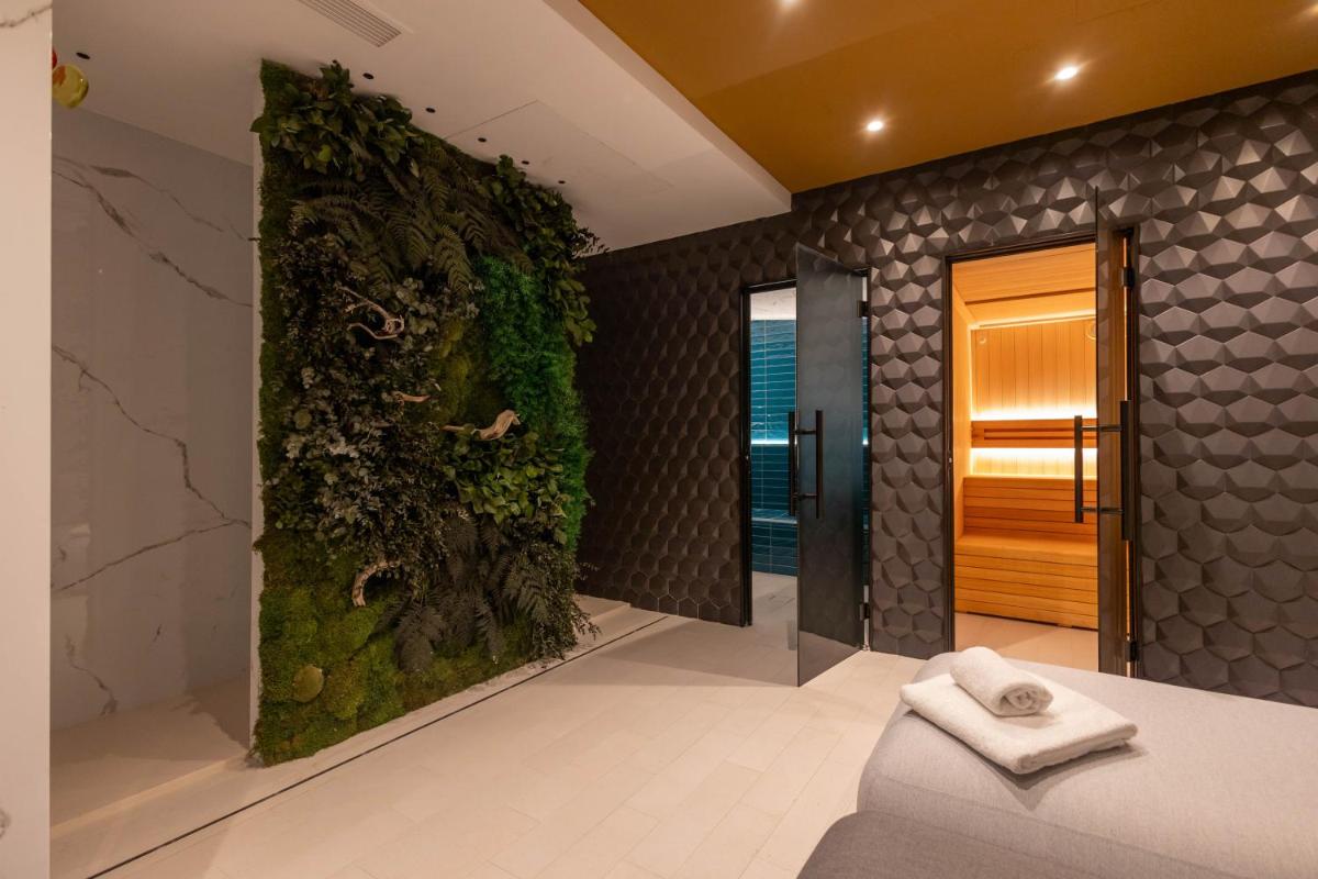Un baño con una pared verde con un sofá y una ducha. en Hotel Neptuno Playa & Spa, en Valencia