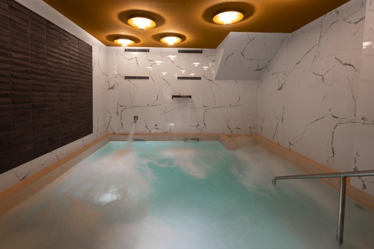 una piscina en una habitación con una pared de piedra en Hotel Neptuno Playa & Spa, en Valencia