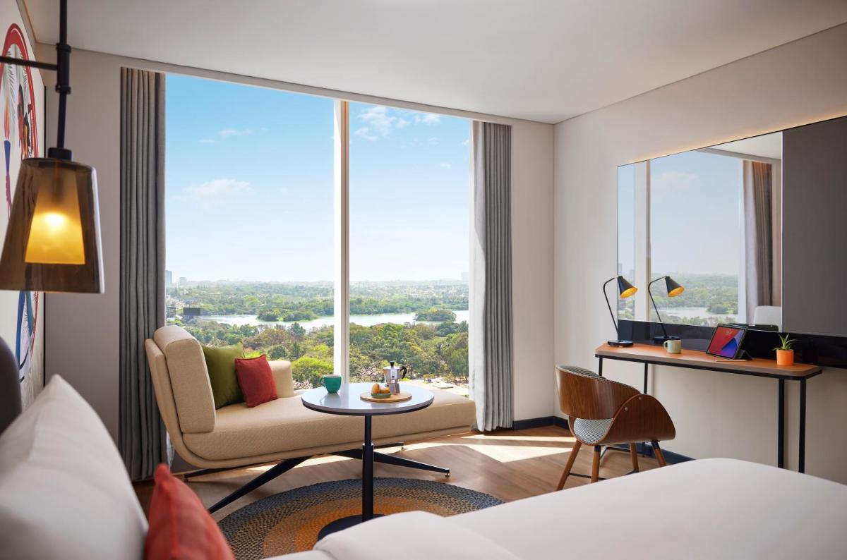 a room with a large window with a couch and a table at Hyatt Centric Hebbal Bengaluru in Bengaluru