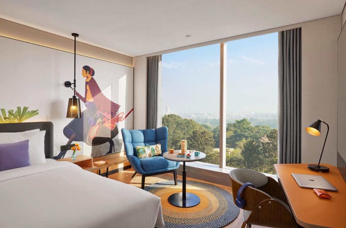 a hotel room with a bed and a large window at Hyatt Centric Hebbal Bengaluru in Bengaluru