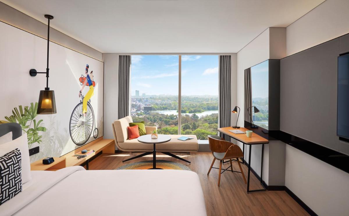 a bedroom with a bed and a living room with a view at Hyatt Centric Hebbal Bengaluru in Bengaluru