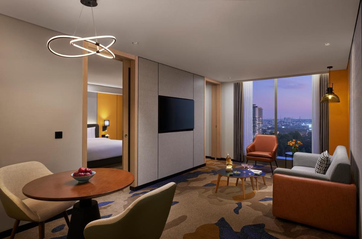 a hotel room with a bed and a living room at Hyatt Centric Hebbal Bengaluru in Bengaluru
