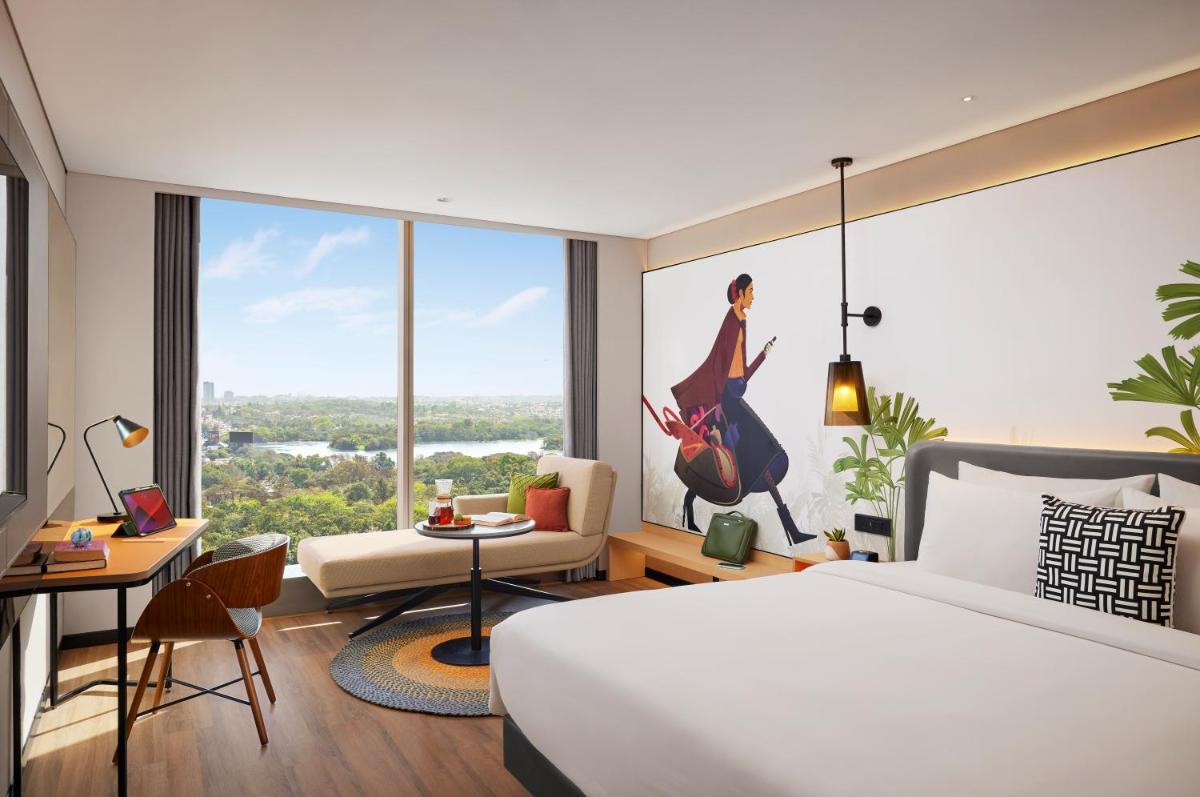a hotel room with a bed and a large window at Hyatt Centric Hebbal Bengaluru in Bengaluru