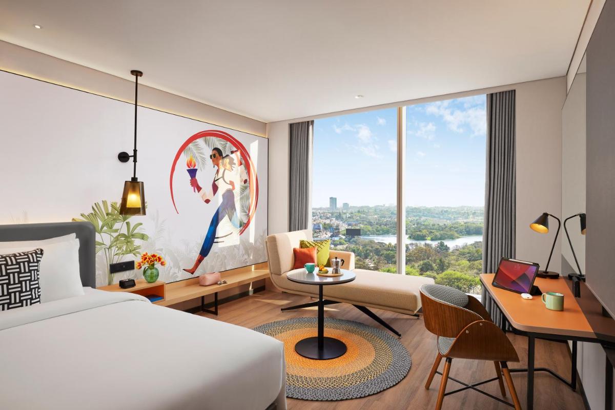 a hotel room with a bed and a large window at Hyatt Centric Hebbal Bengaluru in Bengaluru