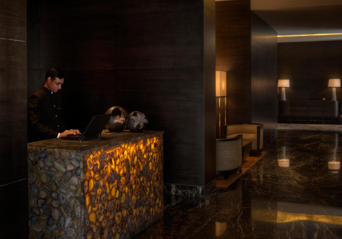 a man working on a laptop in a hotel lobby at Park Hyatt Hotel and Residences, Hyderabad in Hyderabad