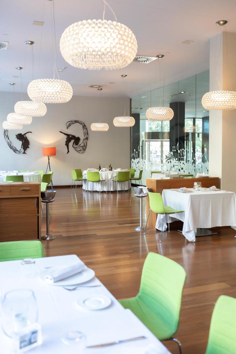 Un comedor con mesas blancas y sillas verdes. en Primus Valencia, en Valencia