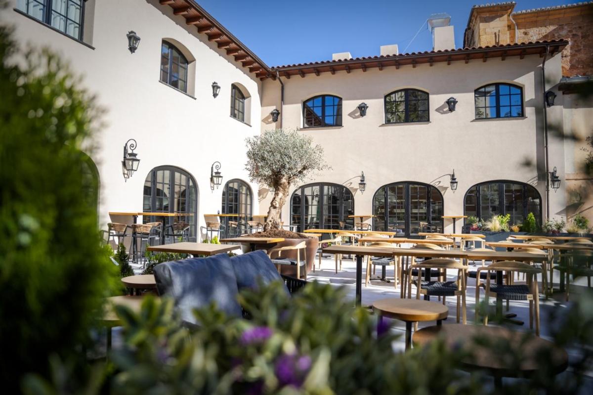 Un patio con mesas y sillas frente a un edificio. en Hotel & Spa Convento San Francisco, en Soria