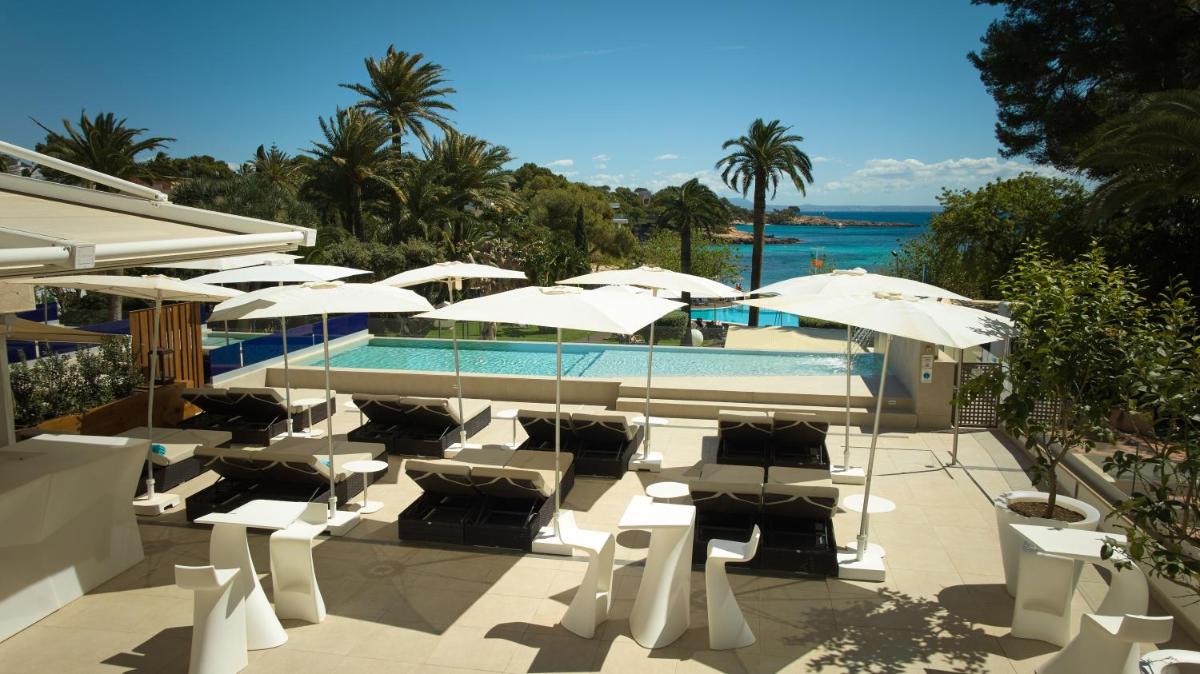 una piscina con sillas y sombrillas blancas en Hotel Son Caliu Spa Oasis, en Palmanova