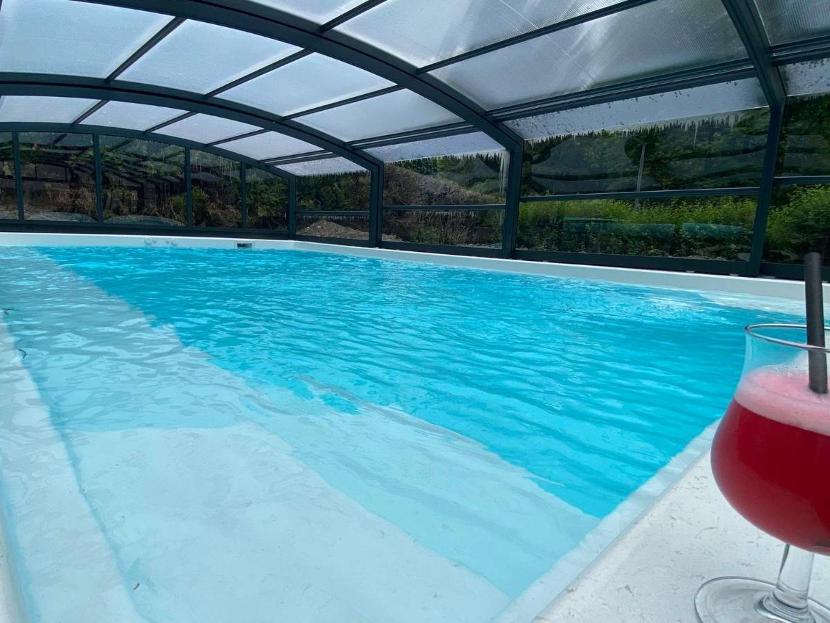 - une piscine avec un verre de vin à côté dans l'établissement BRIT HOTEL & SPA Le Roc au Chien, à Bagnoles-de-l'Orne