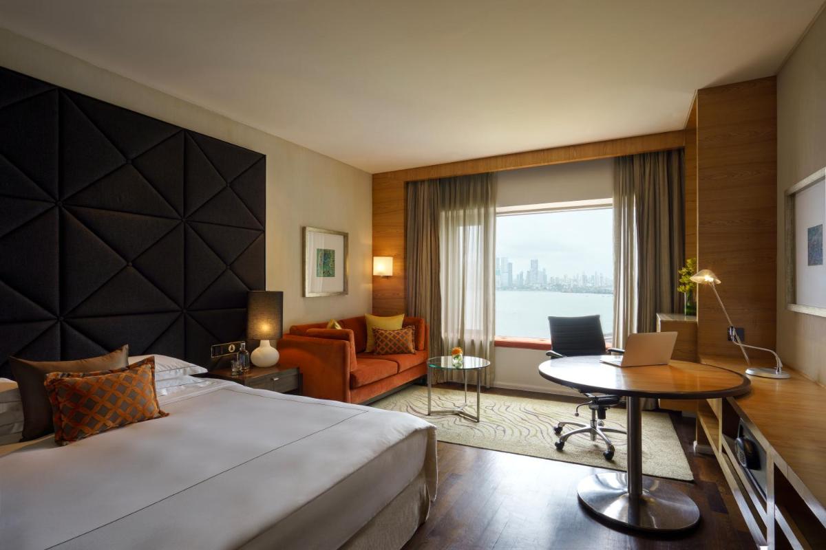 a hotel room with a bed and a desk with a laptop at Taj Lands End in Mumbai a hotel room with a bed and a desk with a laptop at Taj Lands End in Mumbai