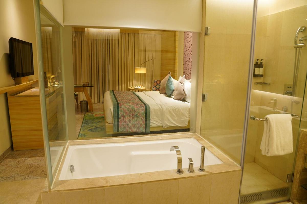 a bathroom with a tub and a bedroom with a bed at Hotel Royal Orchid Jaipur, Tonk Road in Jaipur
