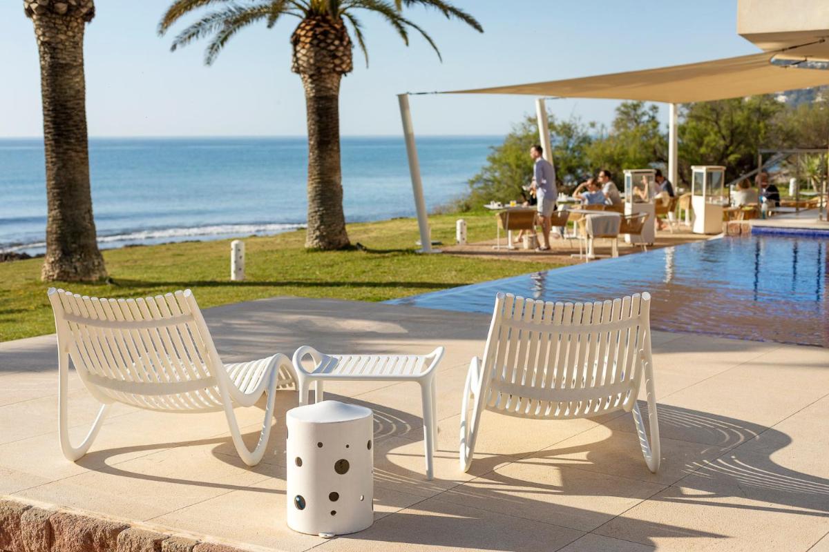 dos sillas blancas sentadas junto a una piscina en Melbeach Hotel & Spa - Adults Only, en Canyamel
