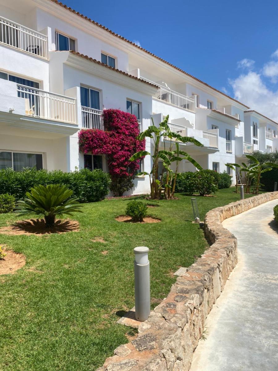 Un edificio de apartamentos blanco con un patio de césped y una calle. en Aparthotel Isla de Cabrera, en Colonia de Sant Jordi
