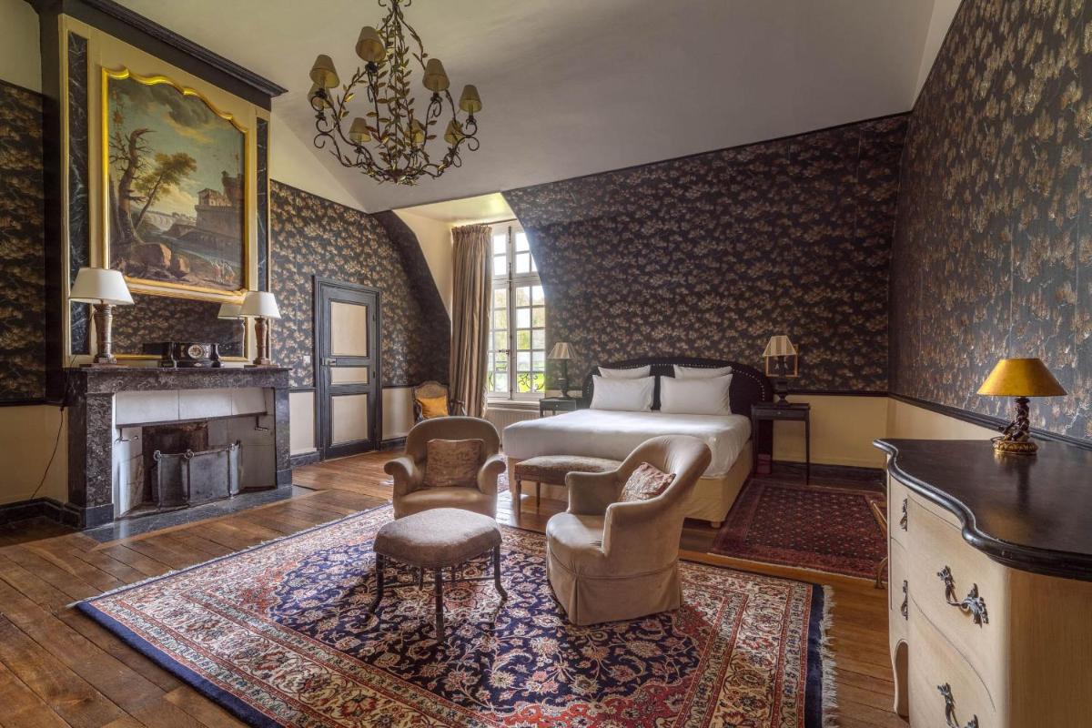 une chambre avec un lit et une cheminée dans l'établissement Le Château d'Etoges - Champagne, à Étoges