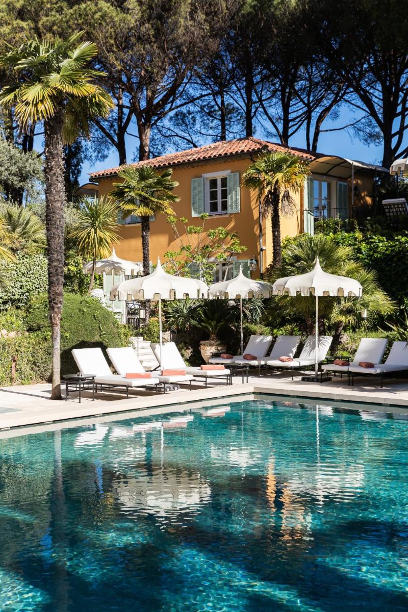 - une piscine avec des chaises et des parasols en face d'une maison dans l'établissement La Bastide de Saint Tropez, à Saint-Tropez