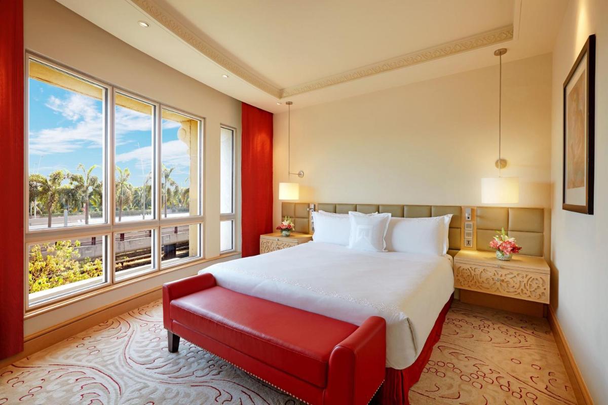 a bedroom with a large bed and a red bench at ITC Maratha, a Luxury Collection Hotel, Mumbai in Mumbai