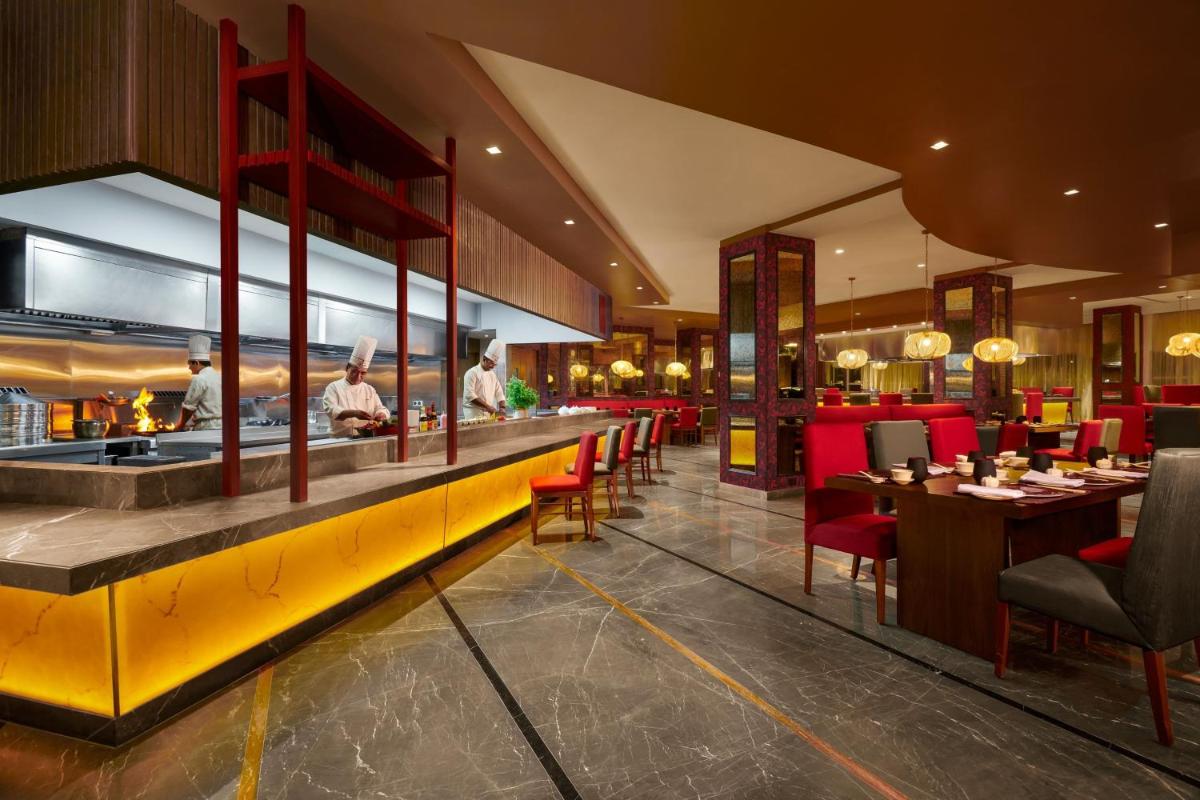 a restaurant with red chairs and a yellow counter at ITC Maratha, a Luxury Collection Hotel, Mumbai in Mumbai