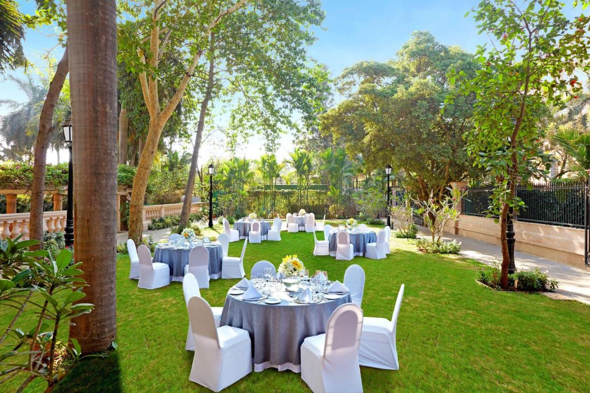 a group of white tables and chairs in a garden at ITC Maratha, a Luxury Collection Hotel, Mumbai in Mumbai