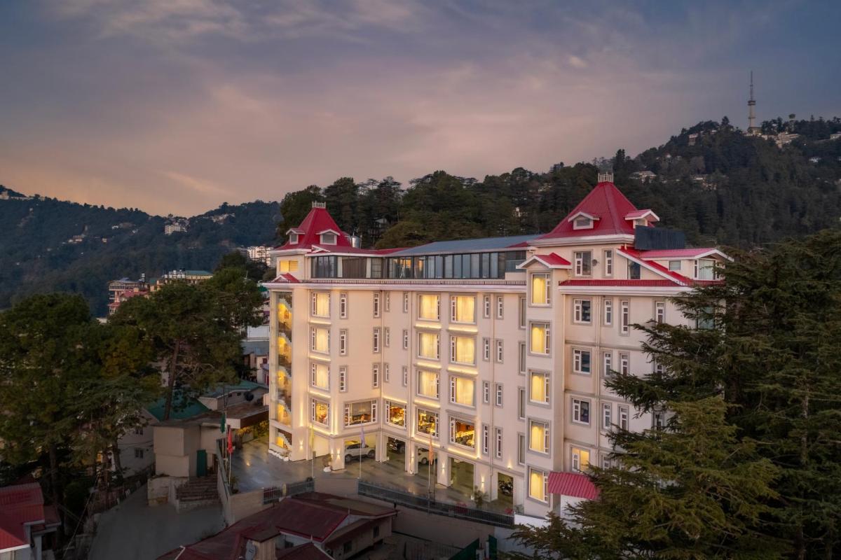 a large white building with a red roof at WelcomHeritage Elysium Resort & Spa in Shimla