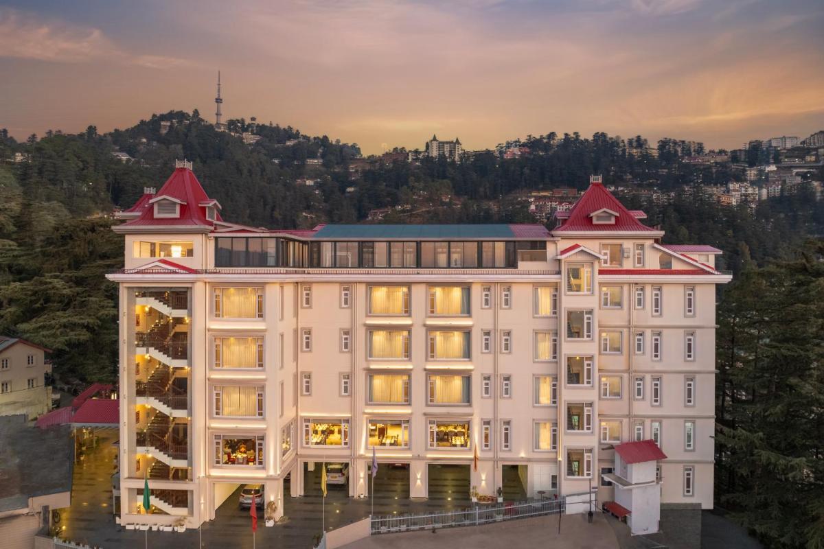 a large white building with red roofs at WelcomHeritage Elysium Resort & Spa in Shimla