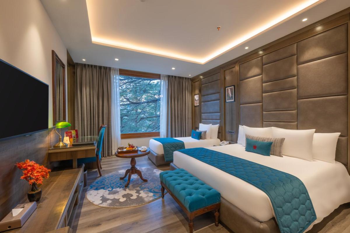 a hotel room with two beds and a television at WelcomHeritage Elysium Resort & Spa in Shimla