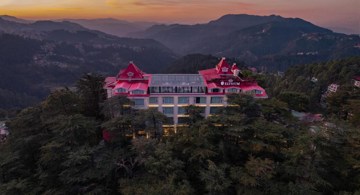 a large pink building on top of a mountain at WelcomHeritage Elysium Resort & Spa in Shimla