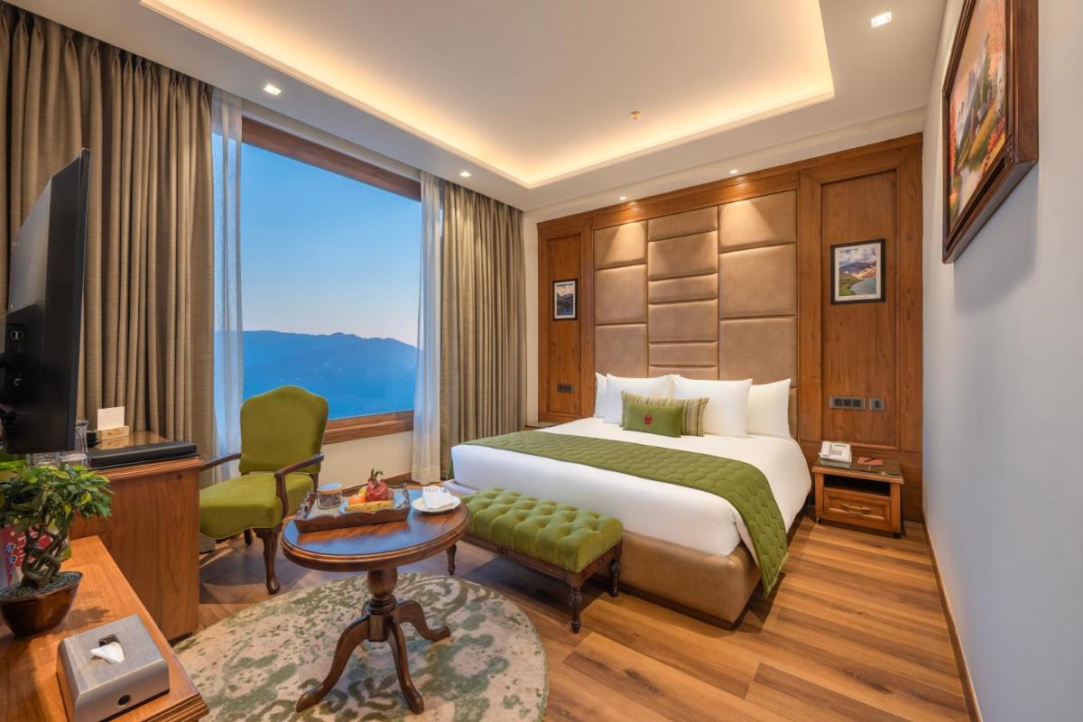 a hotel room with a bed and a large window at WelcomHeritage Elysium Resort & Spa in Shimla +94 photos