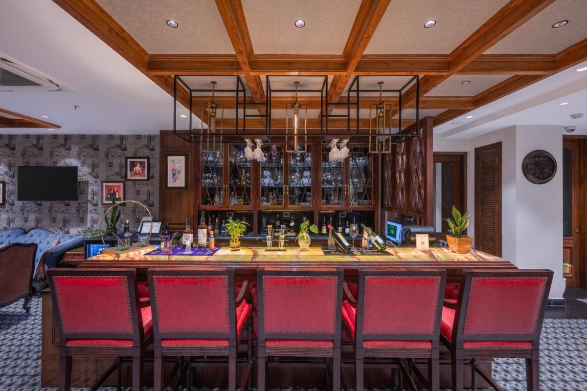 a large bar in a room with red chairs at WelcomHeritage Elysium Resort & Spa in Shimla
