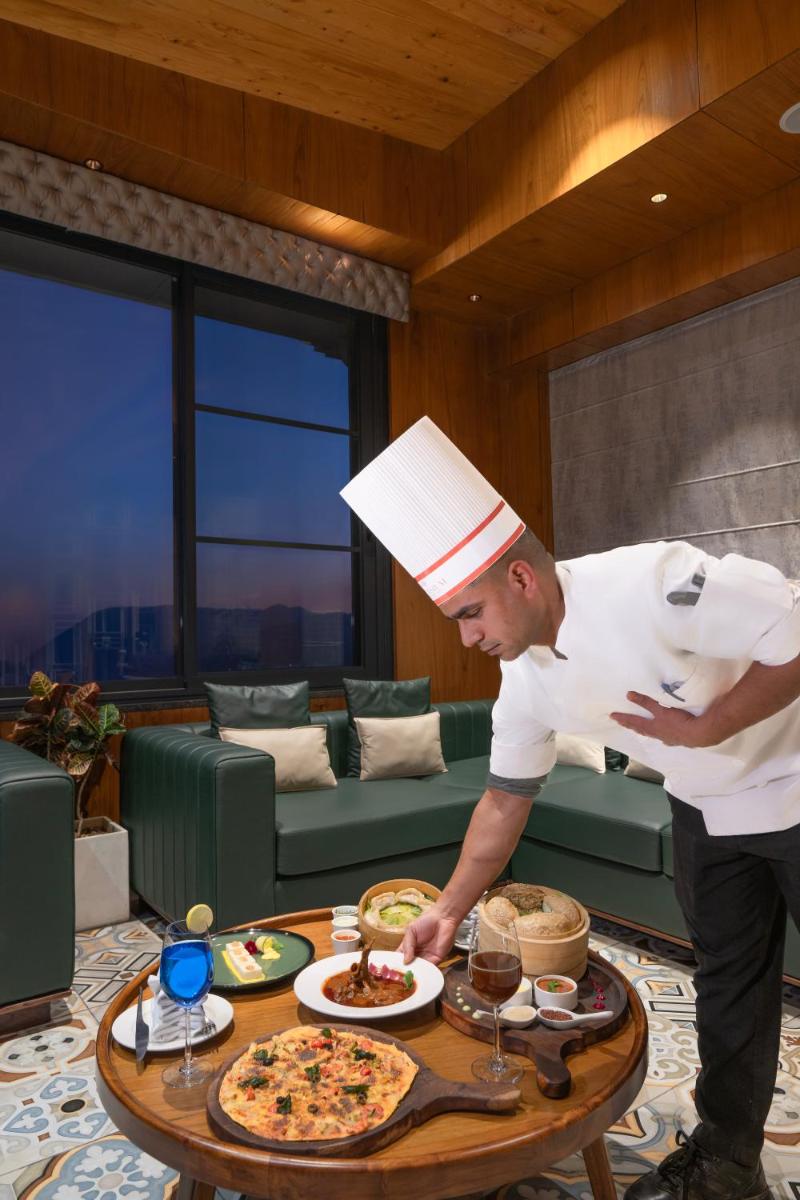 a man in a chefs hat preparing a pizza on a table at WelcomHeritage Elysium Resort & Spa in Shimla