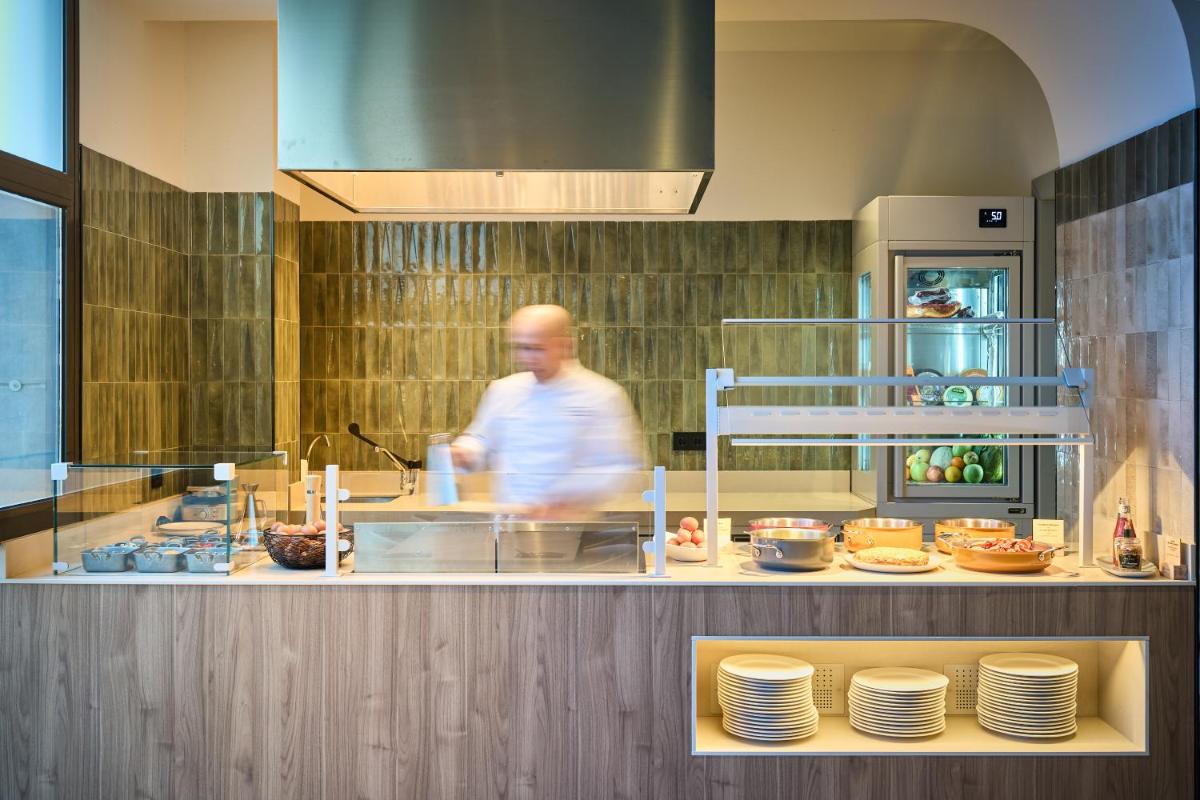 un hombre caminando por delante de un mostrador en una cocina en Catalonia La Maquinista, en Barcelona