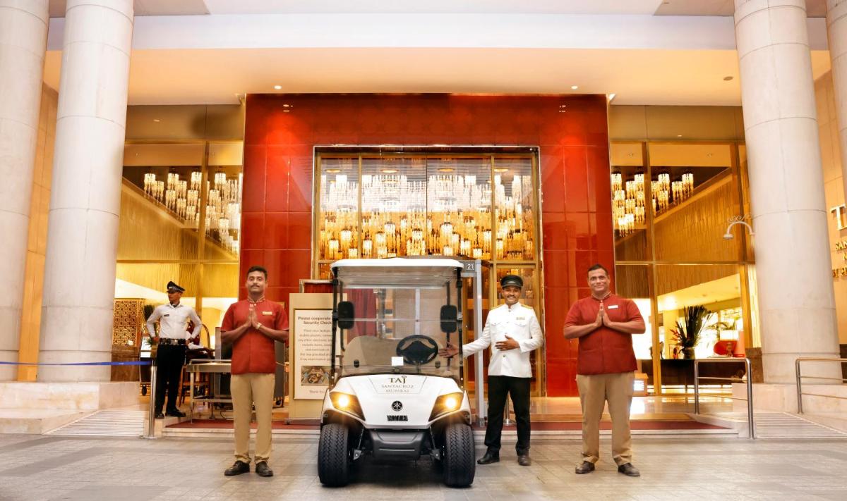 a group of people standing in front of a building with a vehicle at Taj Santacruz in Mumbai