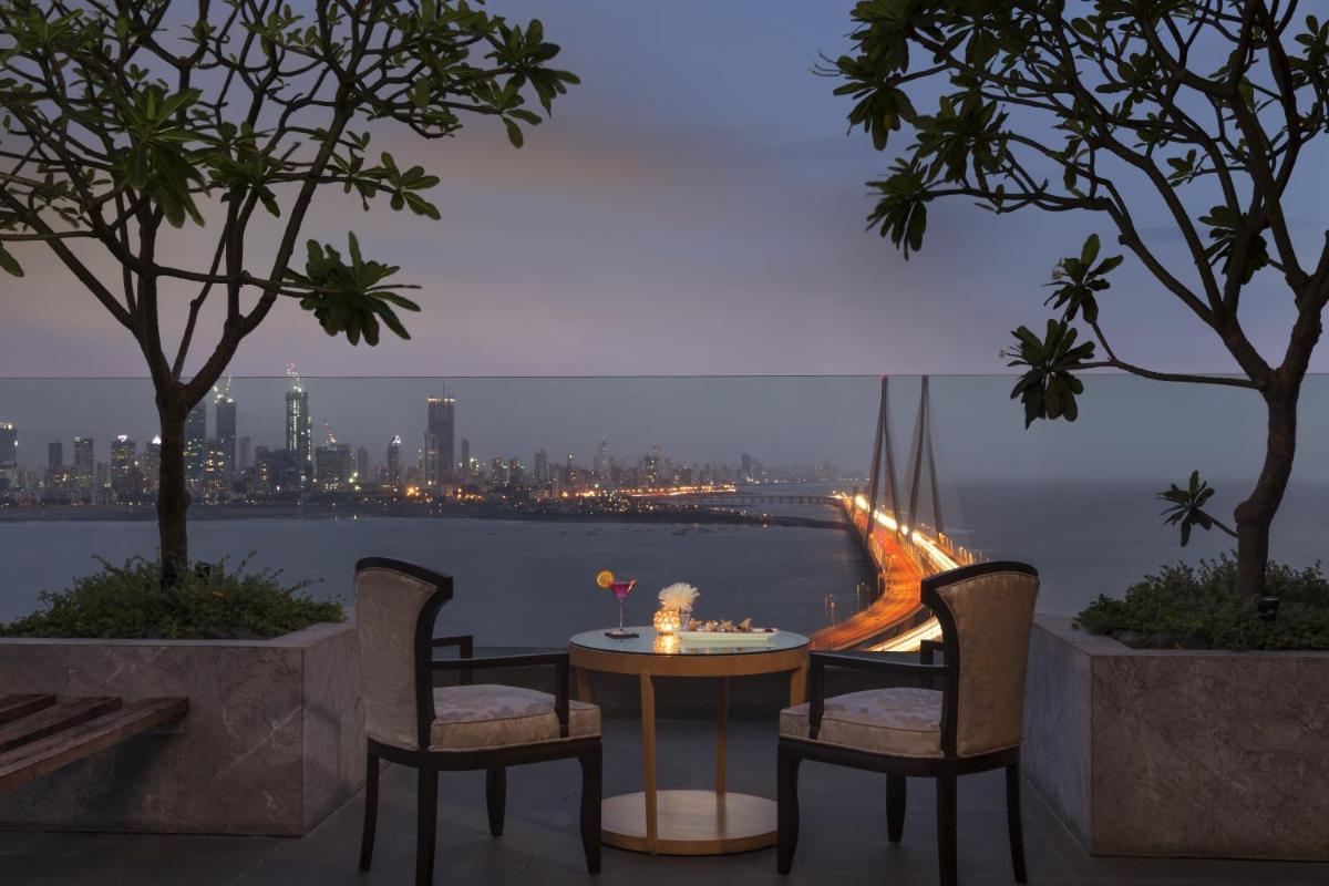 a table and chairs with a view of the city at Taj Lands End in Mumbai a table and chairs with a view of the city at Taj Lands End in Mumbai
