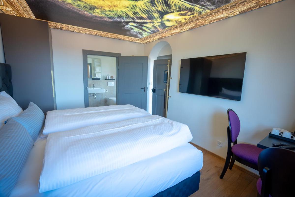ein Hotelzimmer mit zwei Betten und einem Flachbildfernseher in der Unterkunft Maxim Suites by Elias Holl in Augsburg