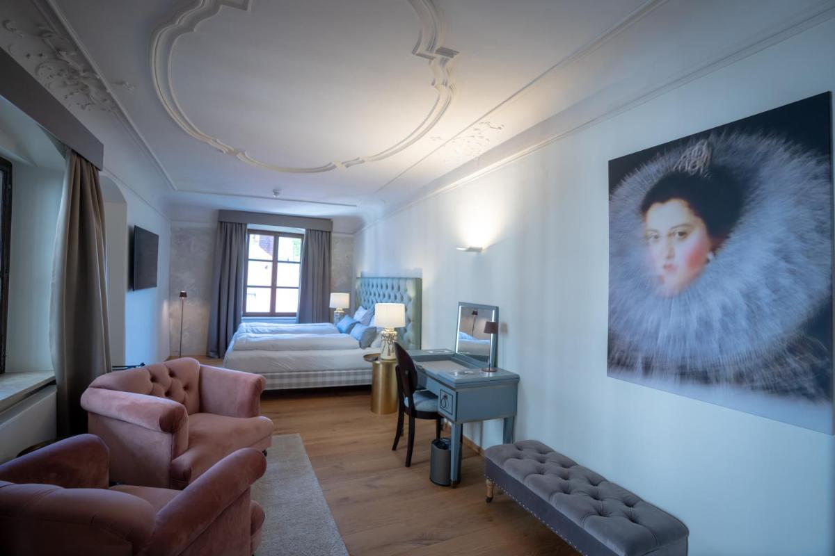 ein Wohnzimmer mit einem Sofa, einem Schreibtisch und einem Bett in der Unterkunft Maxim Suites by Elias Holl in Augsburg