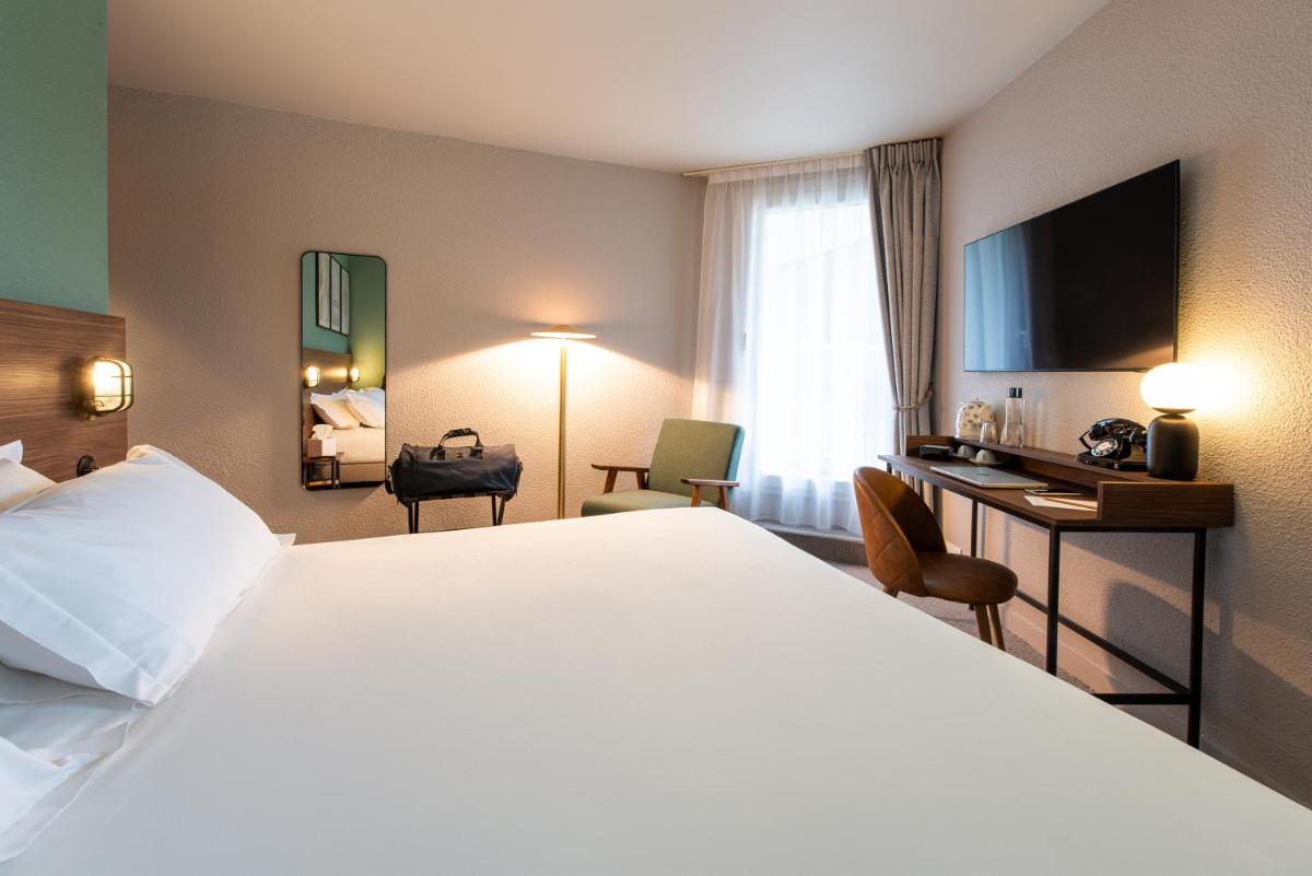 une chambre d'hôtel avec un grand lit et un bureau dans l'établissement La Maison OBONO Hôtel & Spa, au Bono