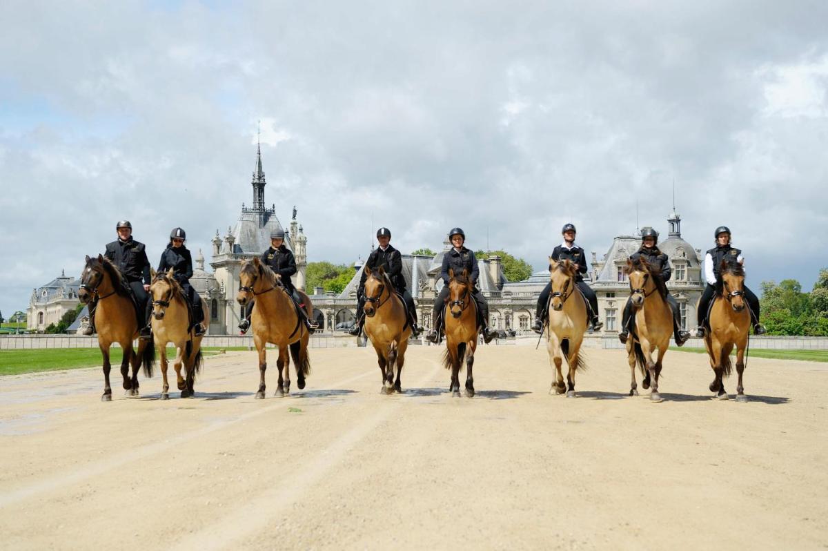 un groupe de personnes à cheval sur un chemin de terre dans l'établissement Auberge du Jeu de Paume, à Chantilly