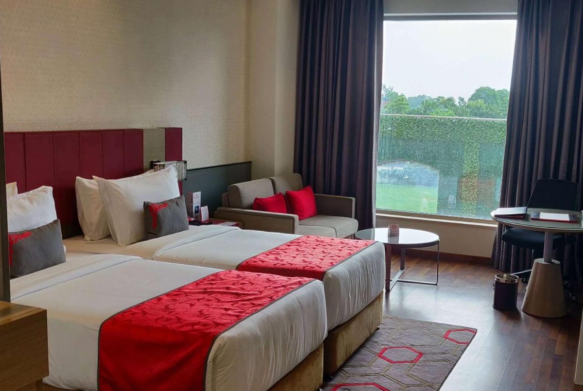 a hotel room with a bed and a large window at Ramada Plaza by Wyndham Lucknow in Lucknow