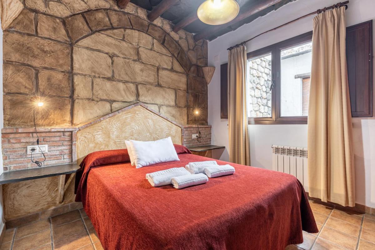 Un dormitorio con una cama roja con toallas. en Turismo Rural & SPA El Cercado, en Bérchules 89 fotos más