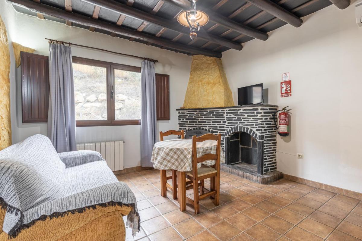 Una sala de estar con una mesa y una chimenea. en Turismo Rural & SPA El Cercado, en Bérchules