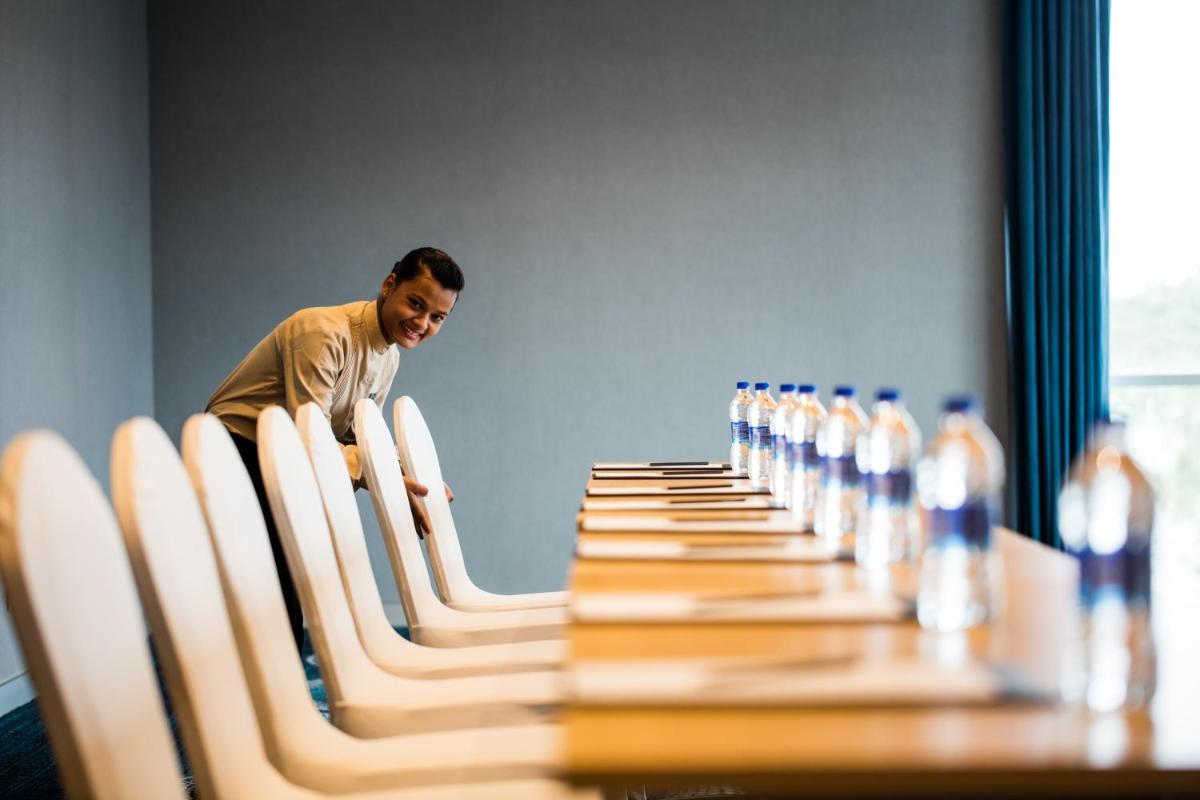 a woman standing in front of a long table with chairs at Oakwood Residence Kapil Hyderabad in Hyderabad