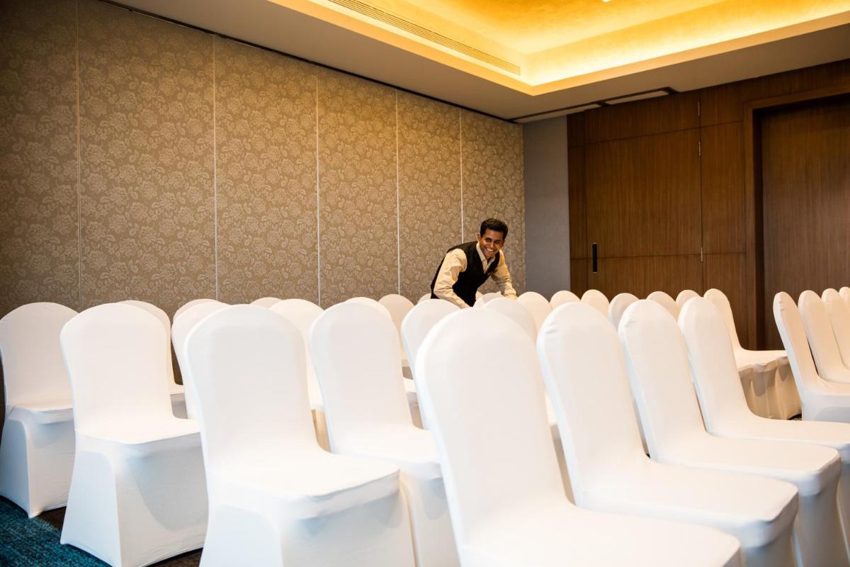 a man standing in a room with white chairs at Oakwood Residence Kapil Hyderabad in Hyderabad