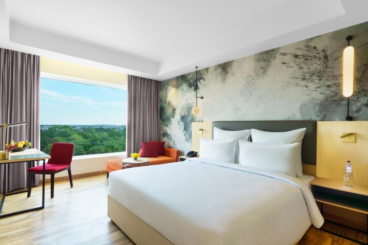 a hotel room with a bed and a large window at Novotel Jaipur Convention Centre in Jaipur