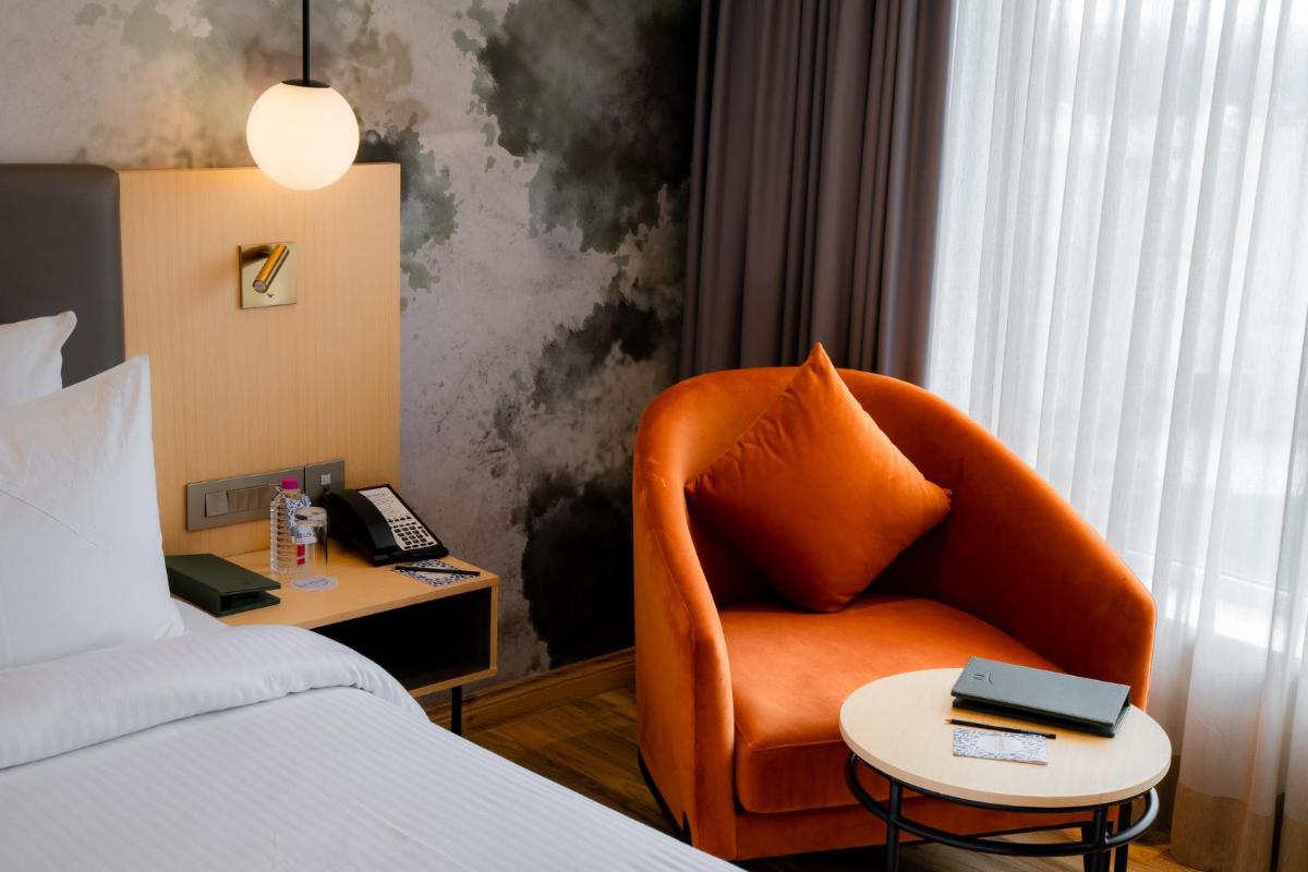 a hotel room with a chair and a bed at Novotel Jaipur Convention Centre in Jaipur
