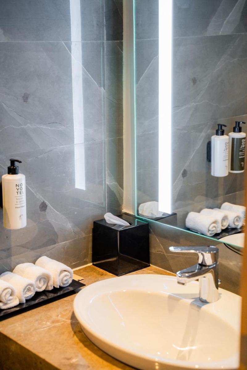 a bathroom with a sink and a mirror and towels at Novotel Jaipur Convention Centre in Jaipur