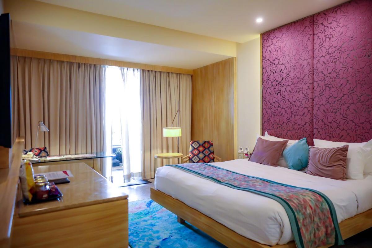 a bedroom with a large bed and a pink wall at Hotel Royal Orchid Jaipur, Tonk Road in Jaipur