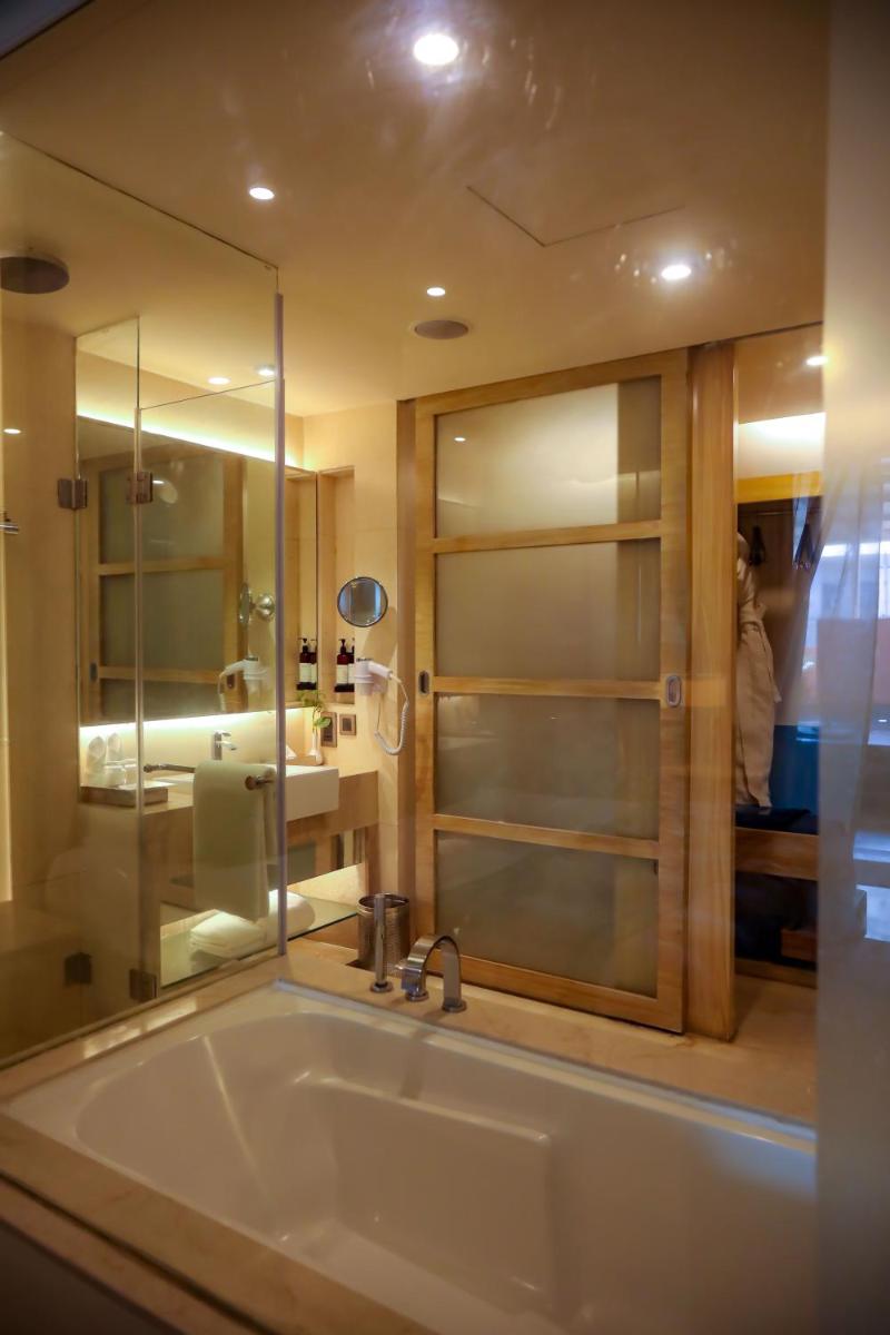 a bathroom with a tub with a shower and a sink at Hotel Royal Orchid Jaipur, Tonk Road in Jaipur