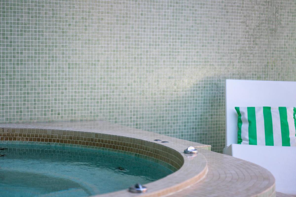 une piscine dans une salle de bains à côté d'un mur carrelé dans l'établissement Boutique Hôtel La Baignoire, à Lacanau-Océan