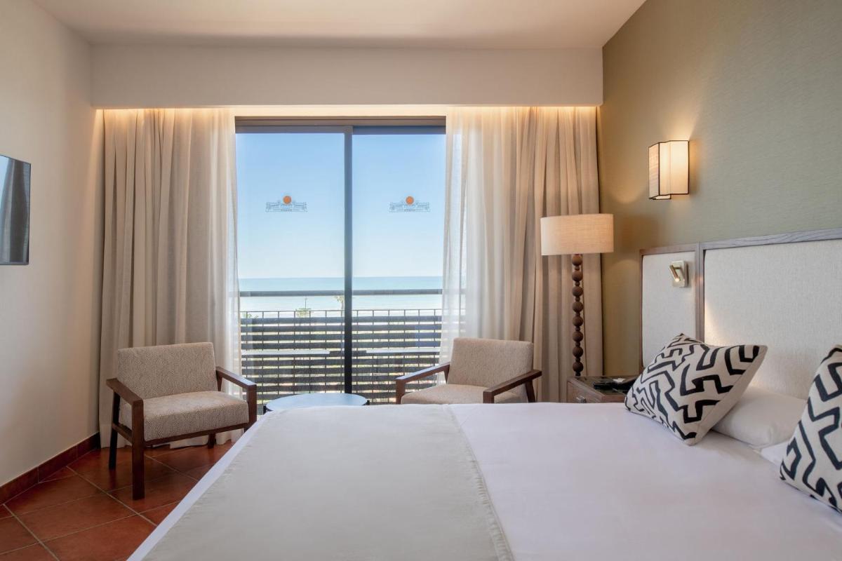 Una habitación de hotel con una cama y una ventana grande. en Puerto Antilla Grand Hotel, en Islantilla 135 fotos más